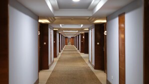 A long, narrow hotel corridor with a carpeted floor, wooden doors, and recessed lighting. - Classic Hotel Muar (Muar)