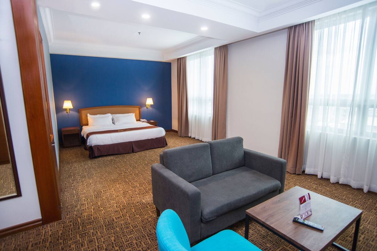 A hotel room with a bed, a sofa, a coffee table, and a TV.