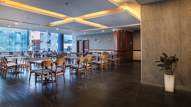 A spacious restaurant with high ceilings, wooden chairs, and tables. - Classic Hotel Muar (Muar)