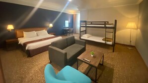 A hotel room with a bed, a sofa, a bunk bed, a small table with a plant, and a lamp. - Classic Hotel Muar (Muar)