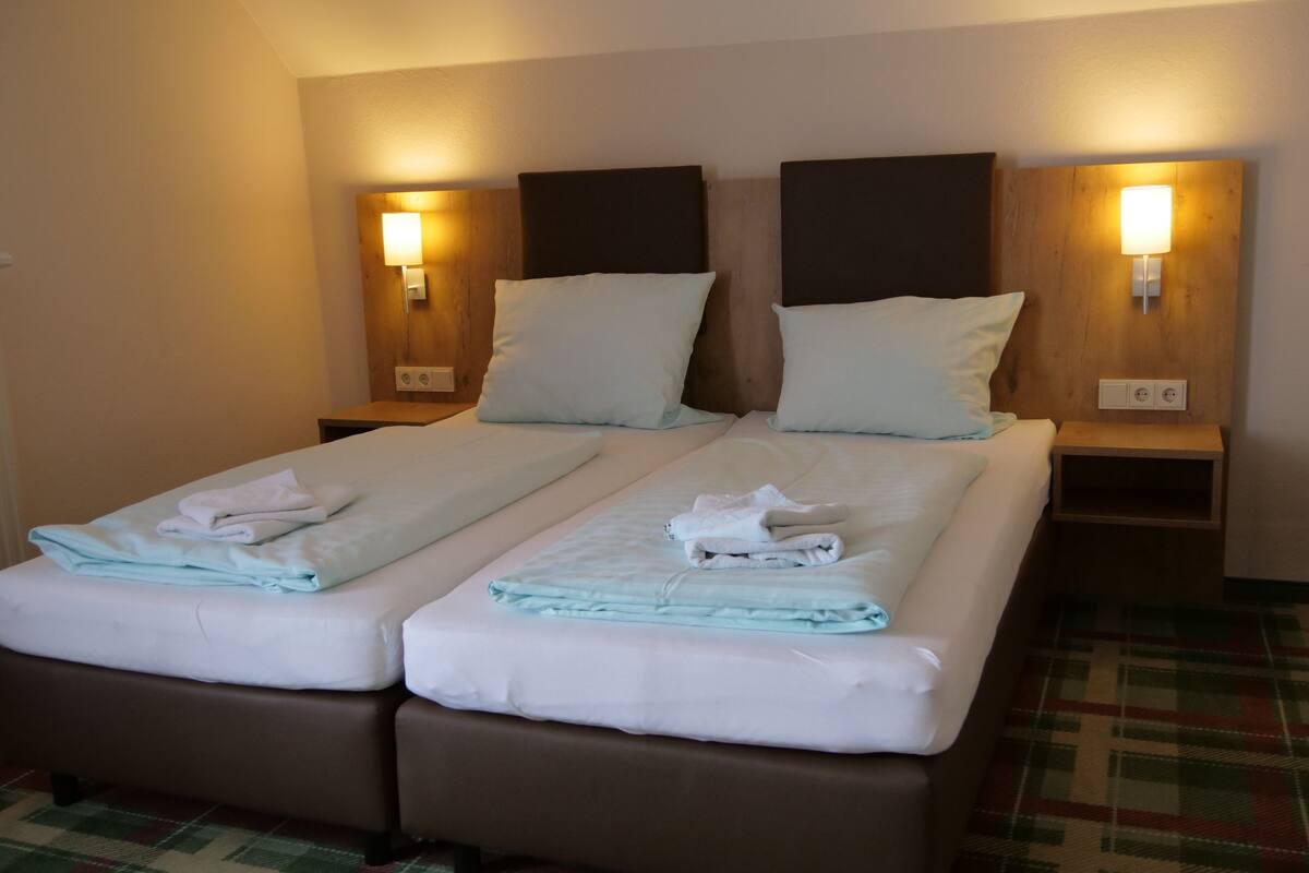 A double bed with two nightstands, each with a wall-mounted lamp.
