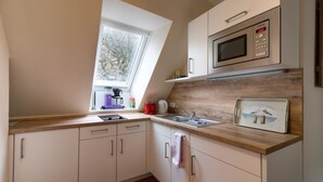 A modern kitchen with a skylight, a microwave, and a sink. - Kajüte Am Nordermarkt (Flensburg)