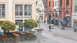A cobblestone square with historic buildings, a fountain, and outdoor seating. - Kajüte Am Nordermarkt (Flensburg)