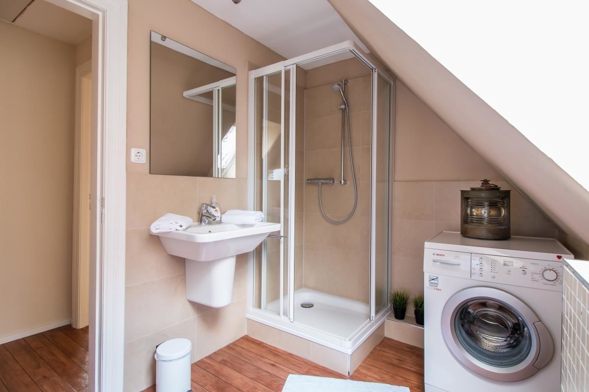 Ein modernes Badezimmer mit Dusche, Waschbecken und Waschmaschine.