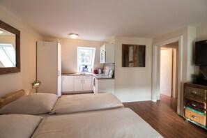 A bedroom with two beds, a kitchenette, a television, and a mirror. - Kajüte Am Nordermarkt (Flensburg)