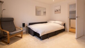A bedroom with a bed, a chair, a bedside table, and a wardrobe.