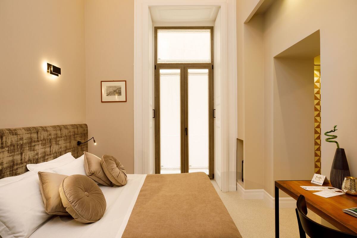 Una habitación de hotel con cama, escritorio y vista al exterior.