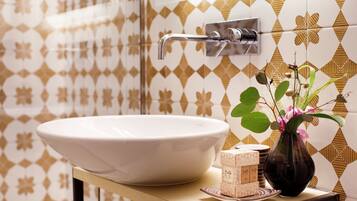 A bathroom with a large white sink, a glass shower enclosure, and patterned tiles.