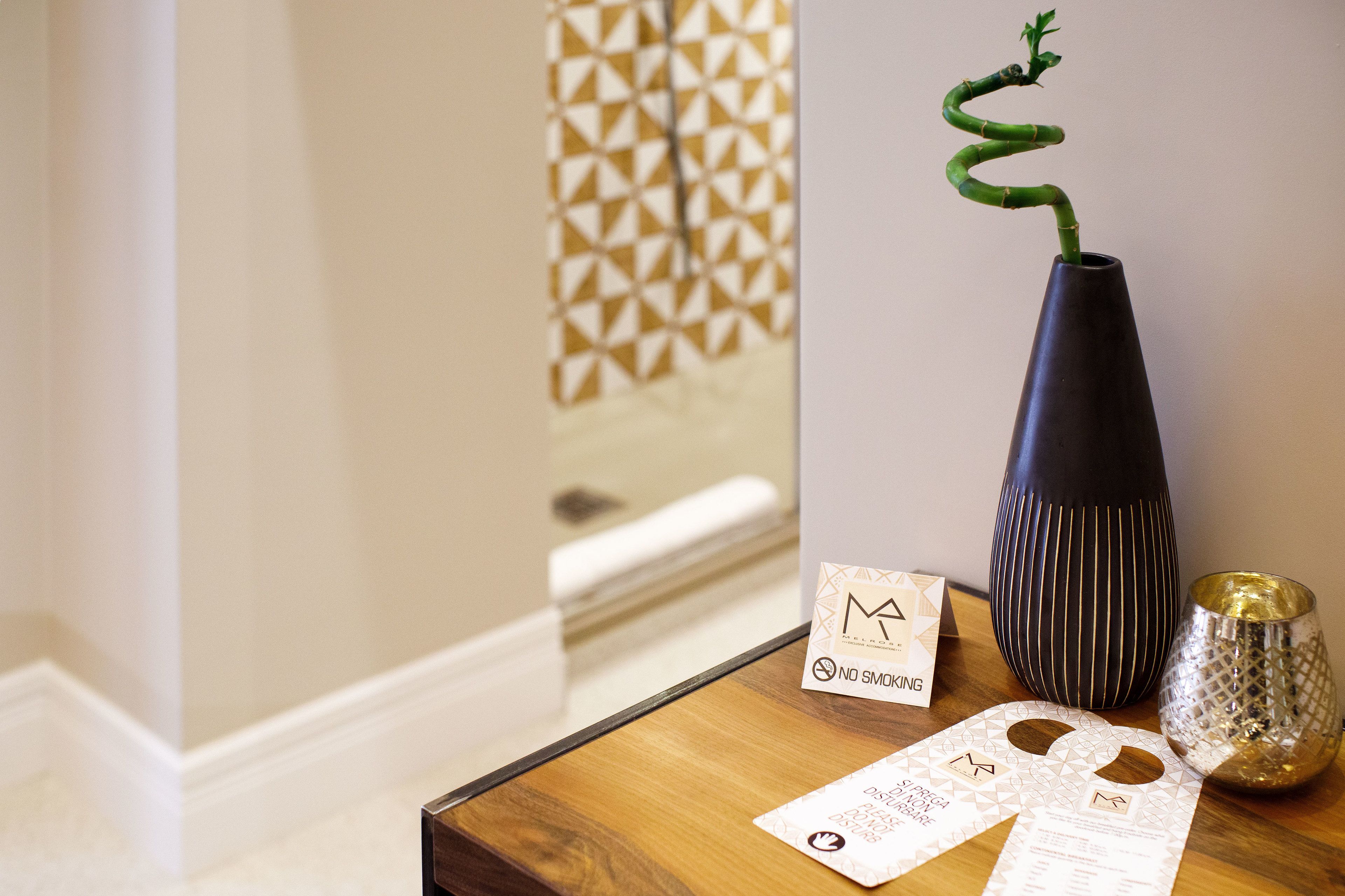 A wooden table with a black vase, a gold candle holder, and a "No Smoking" sign.