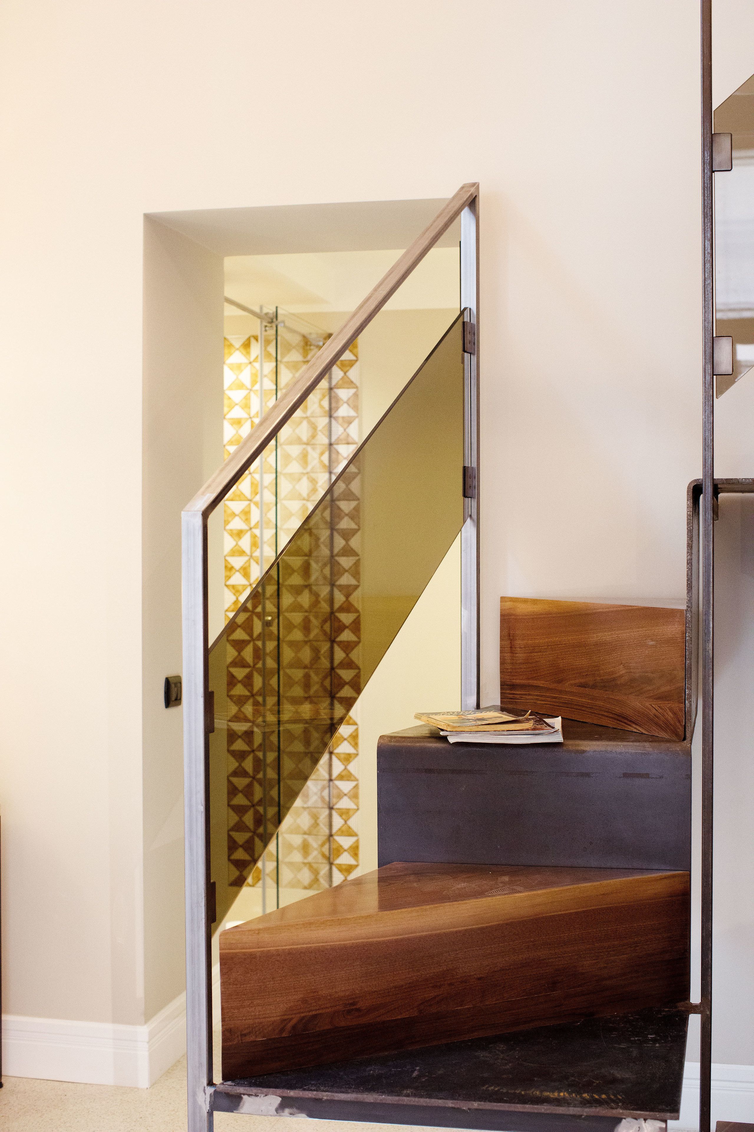 A staircase with a glass railing and a wooden bench.