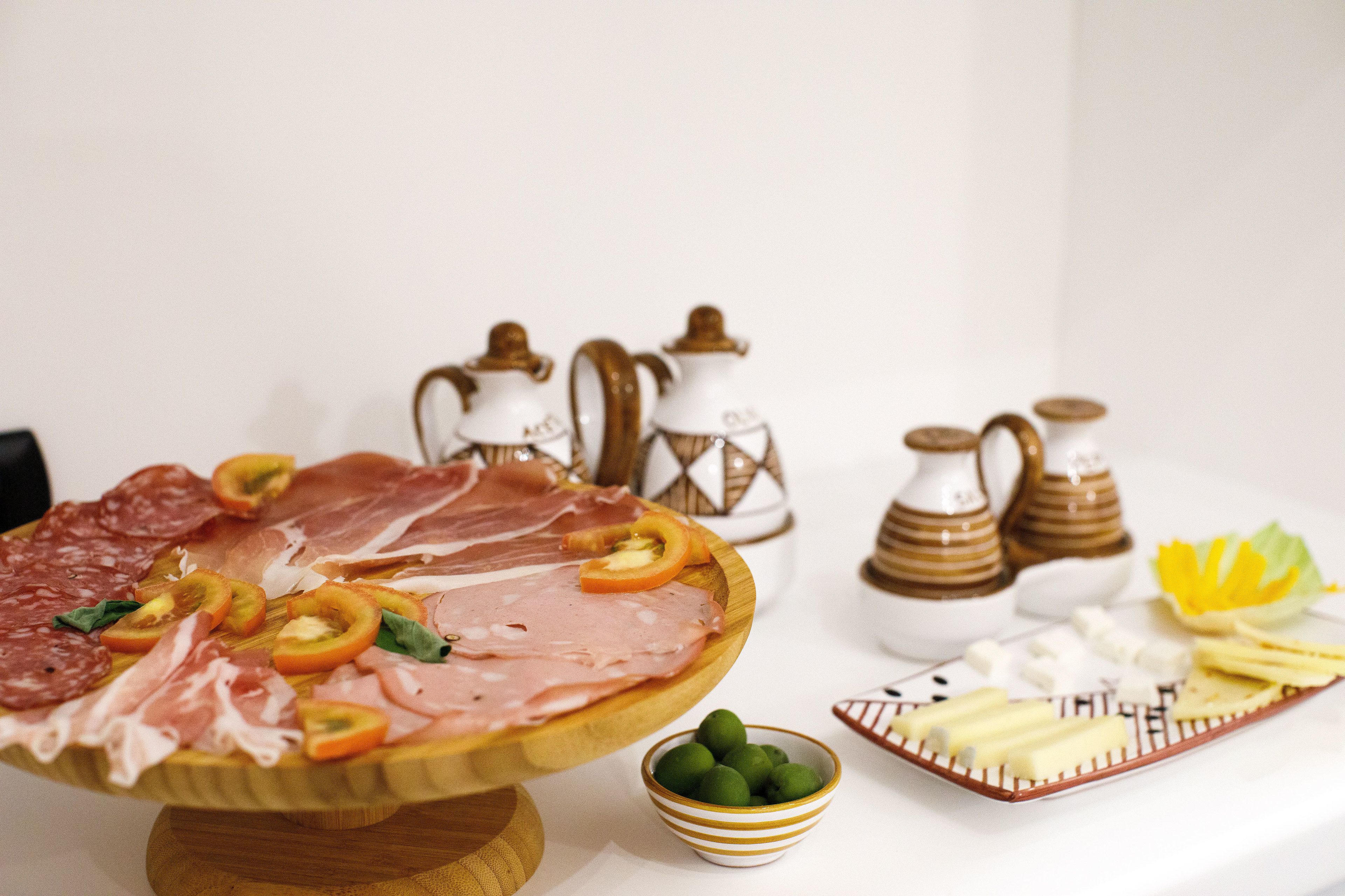 A charcuterie board with various meats, cheeses, and garnishes.