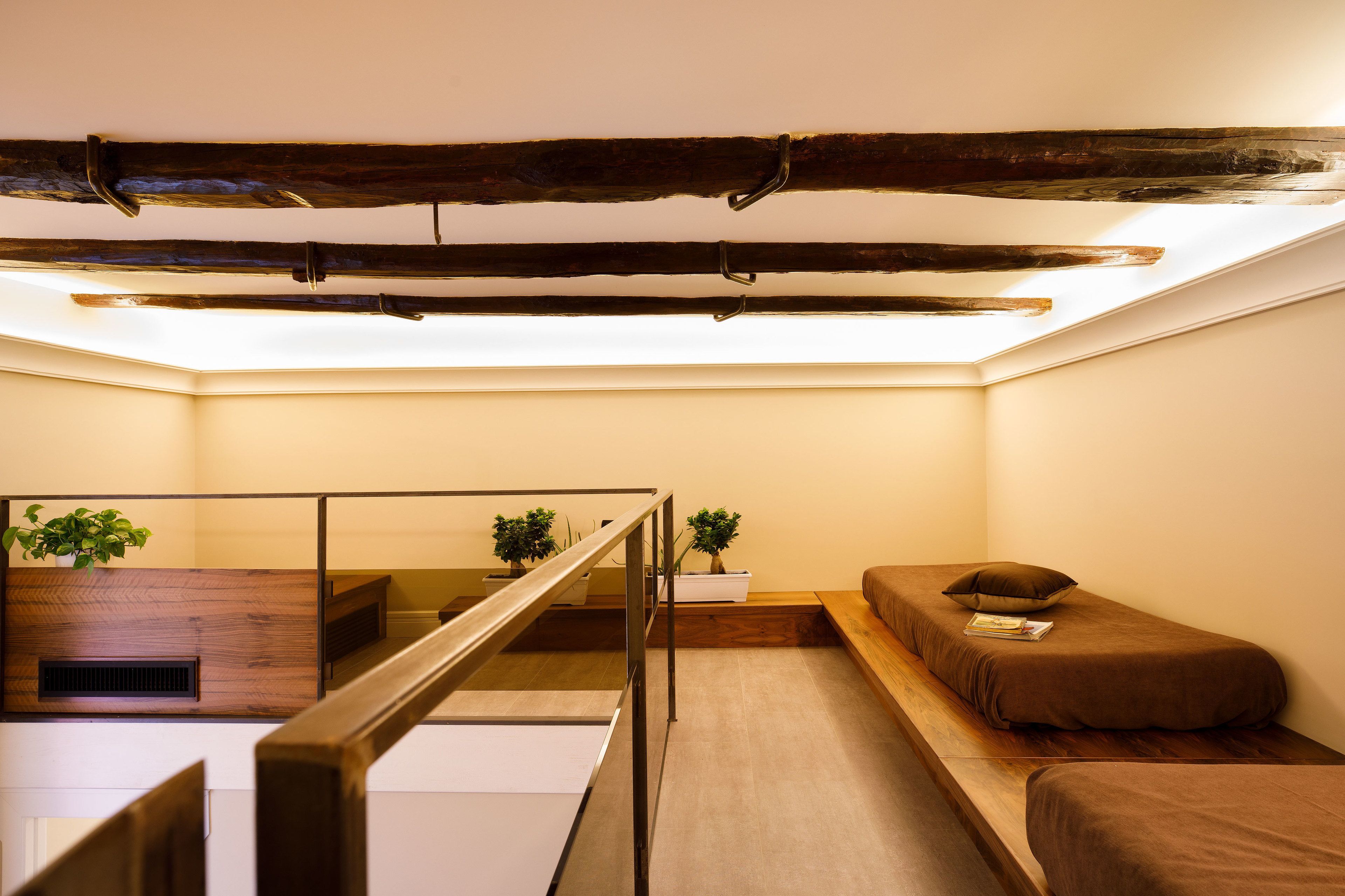 A compact room with a sloped ceiling, a wooden bench, a small bed, and a staircase with a metal railing.