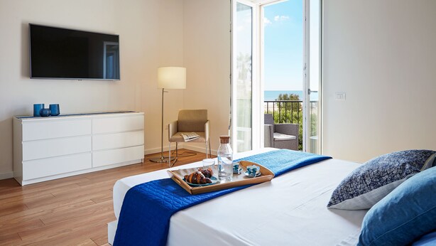 Une chambre avec un lit, une télévision, un bureau et un balcon offrant une vue.