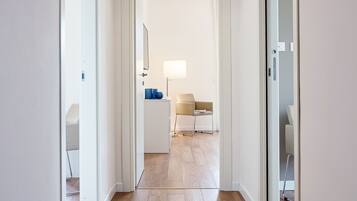 Un pasillo con suelo de madera, paredes blancas y techo con paneles de madera.