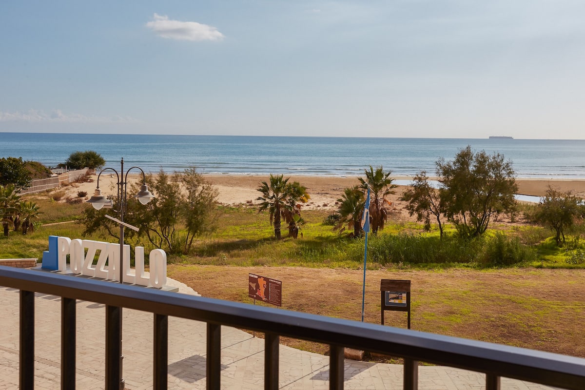 Une vue sur la plage avec un panneau indiquant « POZZALLO ».