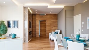 Un espace de salle à manger moderne avec un plancher en bois, des chaises blanches et une table dressée avec de la vaisselle bleue et blanche.