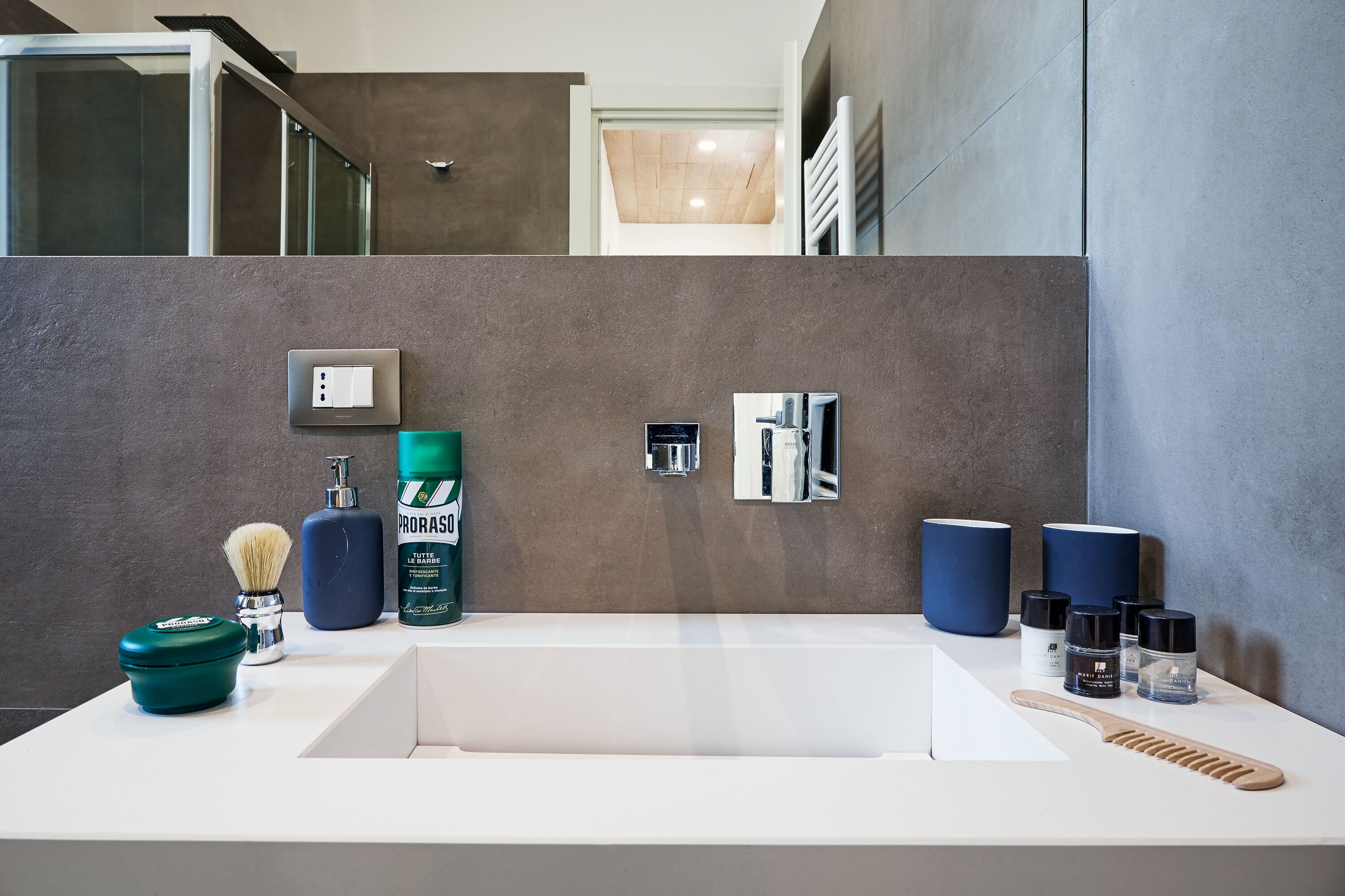 A modern bathroom with a large sink, a mirror, and various toiletries.
