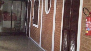 A hallway with arched doorways and a fire extinguisher mounted on the wall. - Vista Alegre Hotel (Ibitinga)