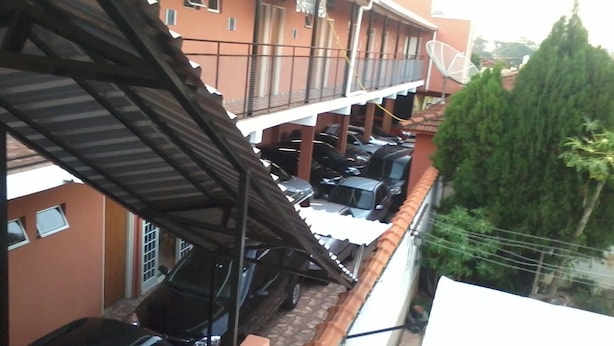 A multi-story building with a balcony, parked cars, and a satellite dish. - Vista Alegre Hotel (Ibitinga)
