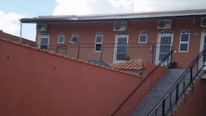A building with a red exterior, a staircase with a metal railing, and a tiled roof. - Vista Alegre Hotel (Ibitinga)