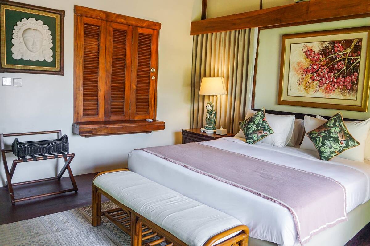 A neatly arranged bedroom with a bed, bedside table, lamp, and a chair.