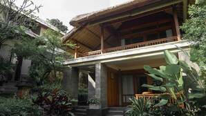 A traditional wooden house with a thatched roof, surrounded by lush greenery and a stone staircase leading to the entrance. - Umah Lawas Ubud (Ubud)