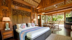 A spacious bedroom with a large bed, wooden headboard, and a balcony with a TV. - Umah Lawas Ubud (Ubud)