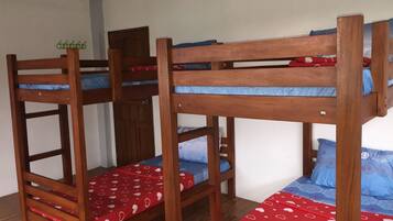 A bunk bed room with two bunk beds, wooden frames, and red and blue bedding.
