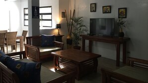 Una sala de estar con sofá, sillones, una mesa de centro, televisor y una planta en maceta.