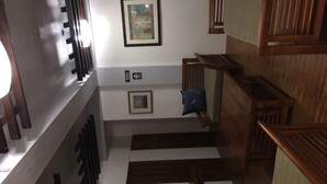 Una escalera con barandillas de madera, un cuadro enmarcado en la pared y una planta pequeña en el suelo.