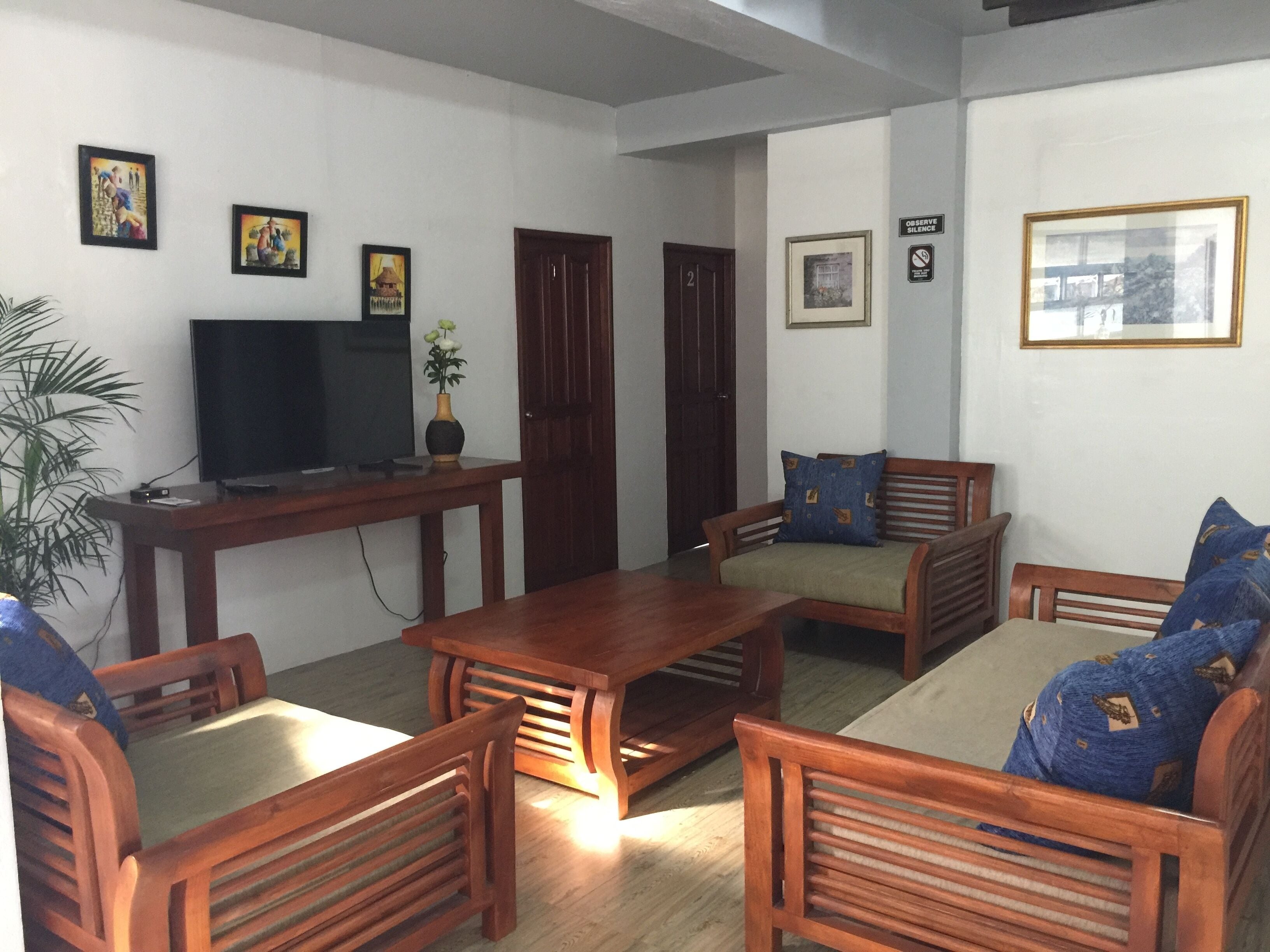 A living room with wooden furniture, a television, and framed pictures on the walls.