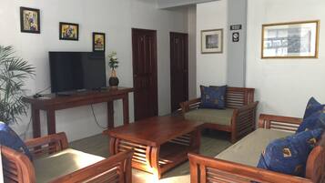 A living room with wooden furniture, a television, and framed pictures on the walls.