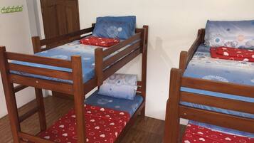 A room with two bunk beds, each with a blue and white patterned bedspread, red heart-patterned pillows, and a wooden headboard.