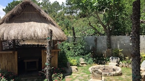 Eine rustikale Lehmhütte mit Strohdach und Holztür, umgeben von einem Garten mit trittfesten Steinen, Steinen und blühenden Pflanzen.