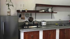 Eine kleine Küche mit Kühlschrank, Herd und Holzschränken.