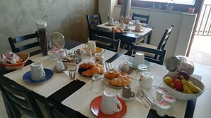 A breakfast setup with croissants, coffee, and fruit on a table in a room with a view. - Guest House Domus Cicerone (Formia)