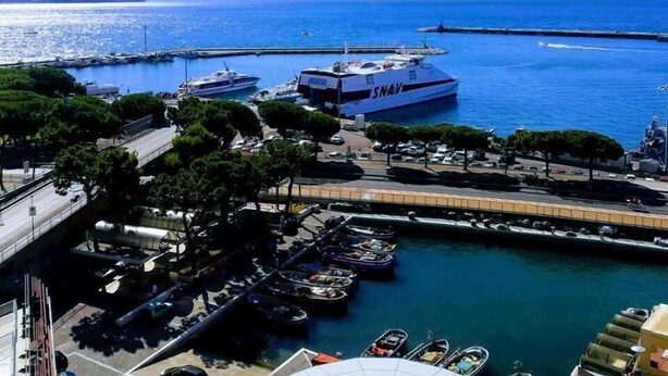 A marina with boats docked, a large white yacht with 'SNAV' on it, and a clear view of the sea and distant mountains. - Guest House Domus Cicerone (Formia)