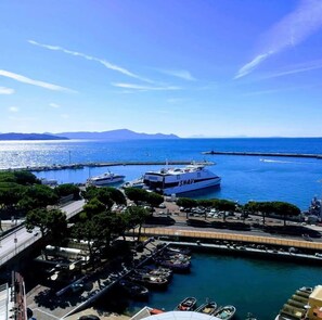 A marina with boats docked, a large white yacht with 'SNAV' on it, and a clear view of the sea and distant mountains. - Guest House Domus Cicerone (Formia)