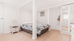 Una camera da letto con un letto, un comodino, uno specchio e una porta.