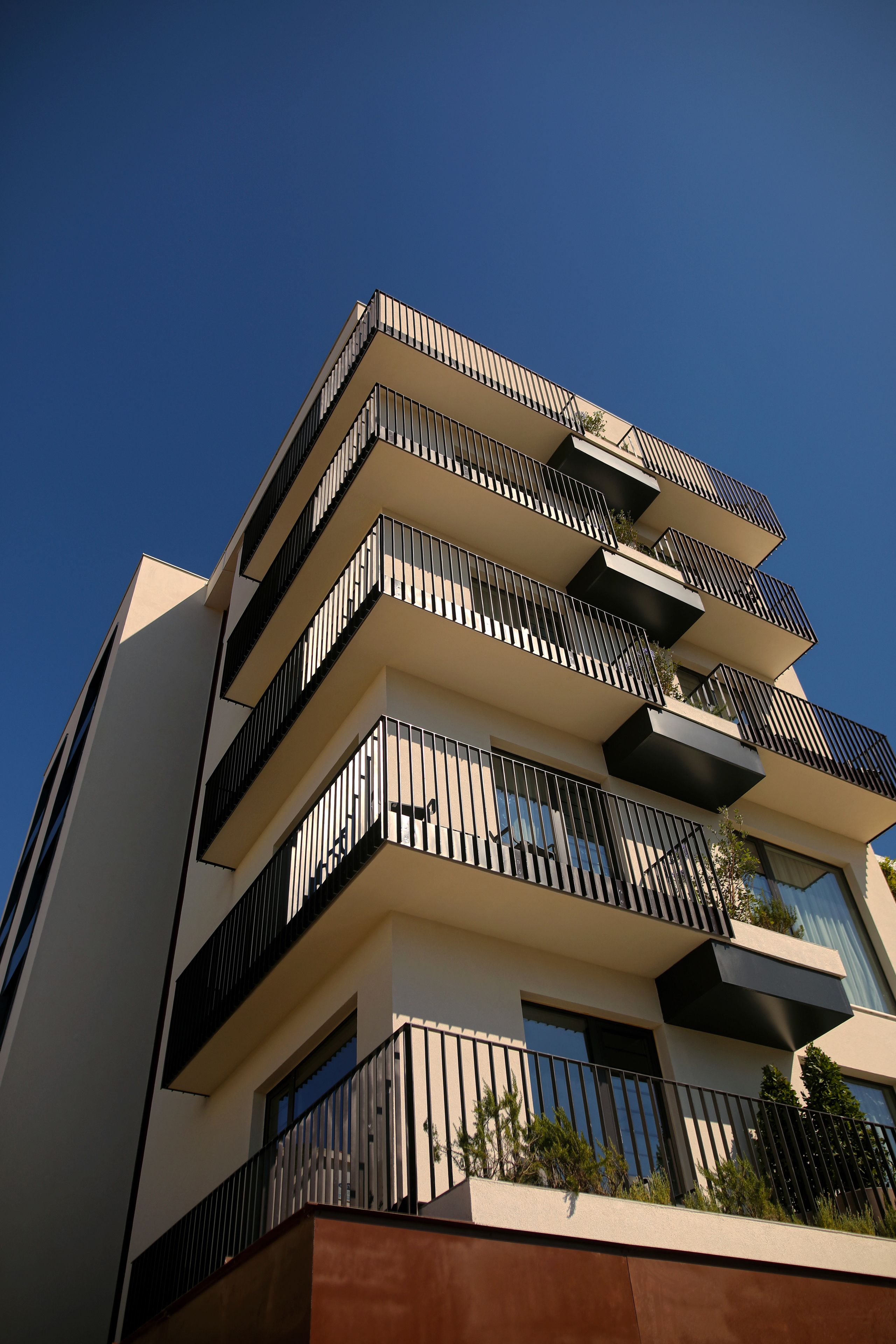 Un edificio de varios pisos con balcones, cielo despejado y un estilo arquitectónico moderno.