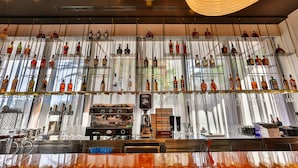 Zona de bar con múltiples estantes de botellas de licor, una máquina de café y utensilios de bar.