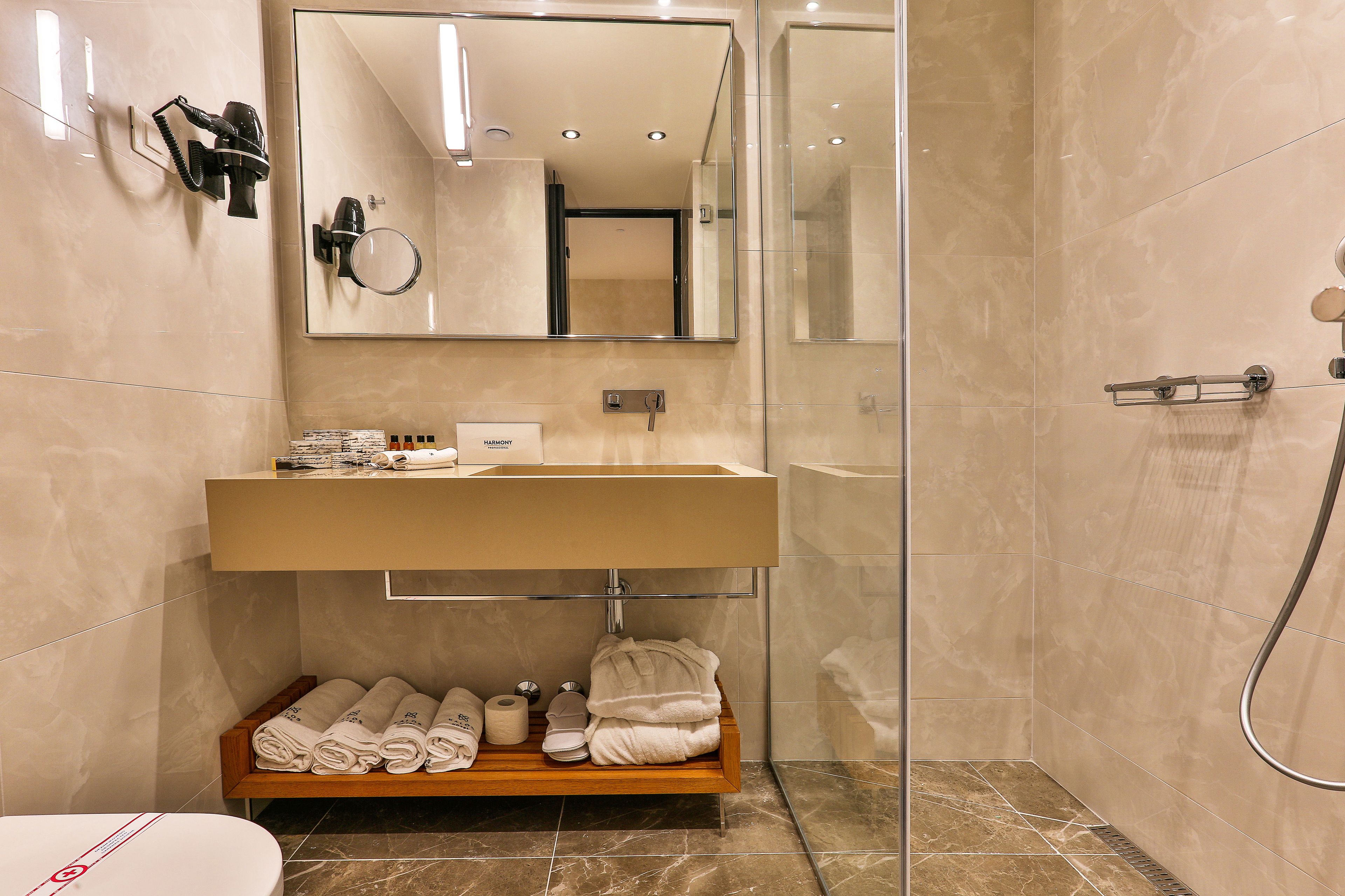 A modern bathroom with a large mirror, a sink, and a shower.