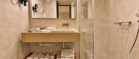 Un baño moderno con un espejo grande, un lavamanos y una ducha.