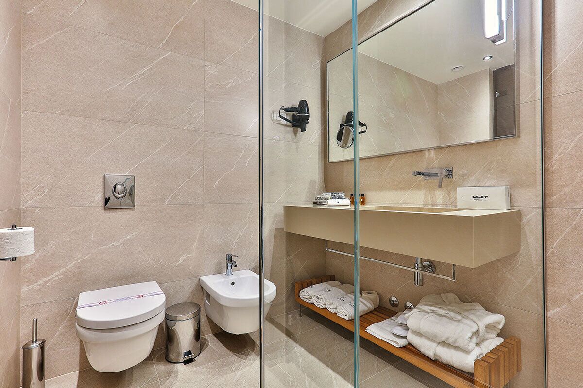 Ein modernes Badezimmer mit Toilette, Bidet, Waschbecken und einer Duschkabine aus Glas.