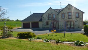 A two-story house with a garage, a swing set, and a stone lamp post in the yard. - Chambres d'Hotes Bel Air (La Selle-Craonnaise)