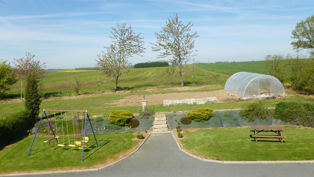A park with a swing set, a greenhouse, and a picnic table. - Chambres d'Hotes Bel Air (La Selle-Craonnaise)