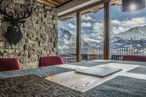 A dining area with a stone wall, a mounted deer head, and a table with placemats.