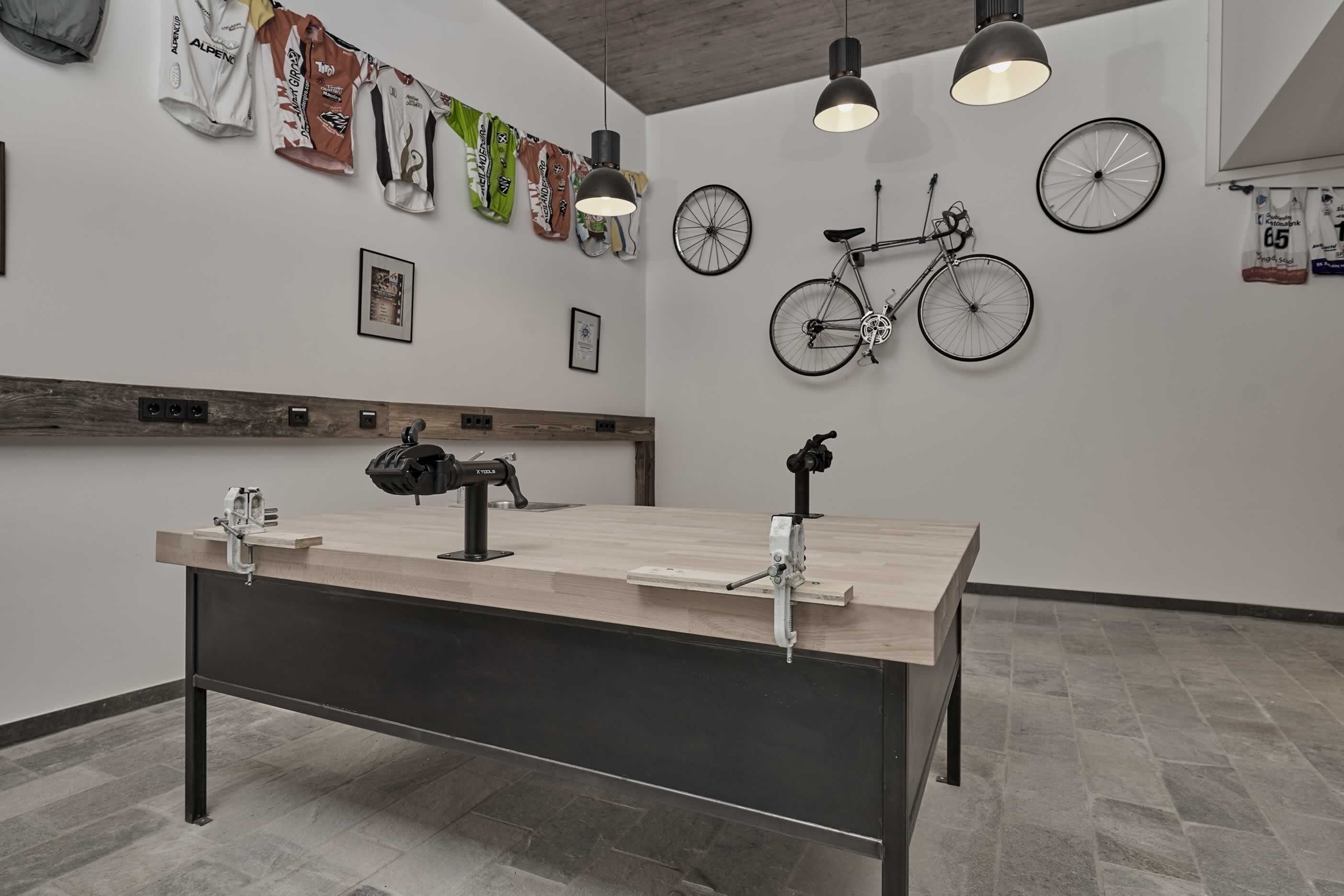 Une pièce moderne avec une longue table, des vélos fixés au mur et des maillots de sport.