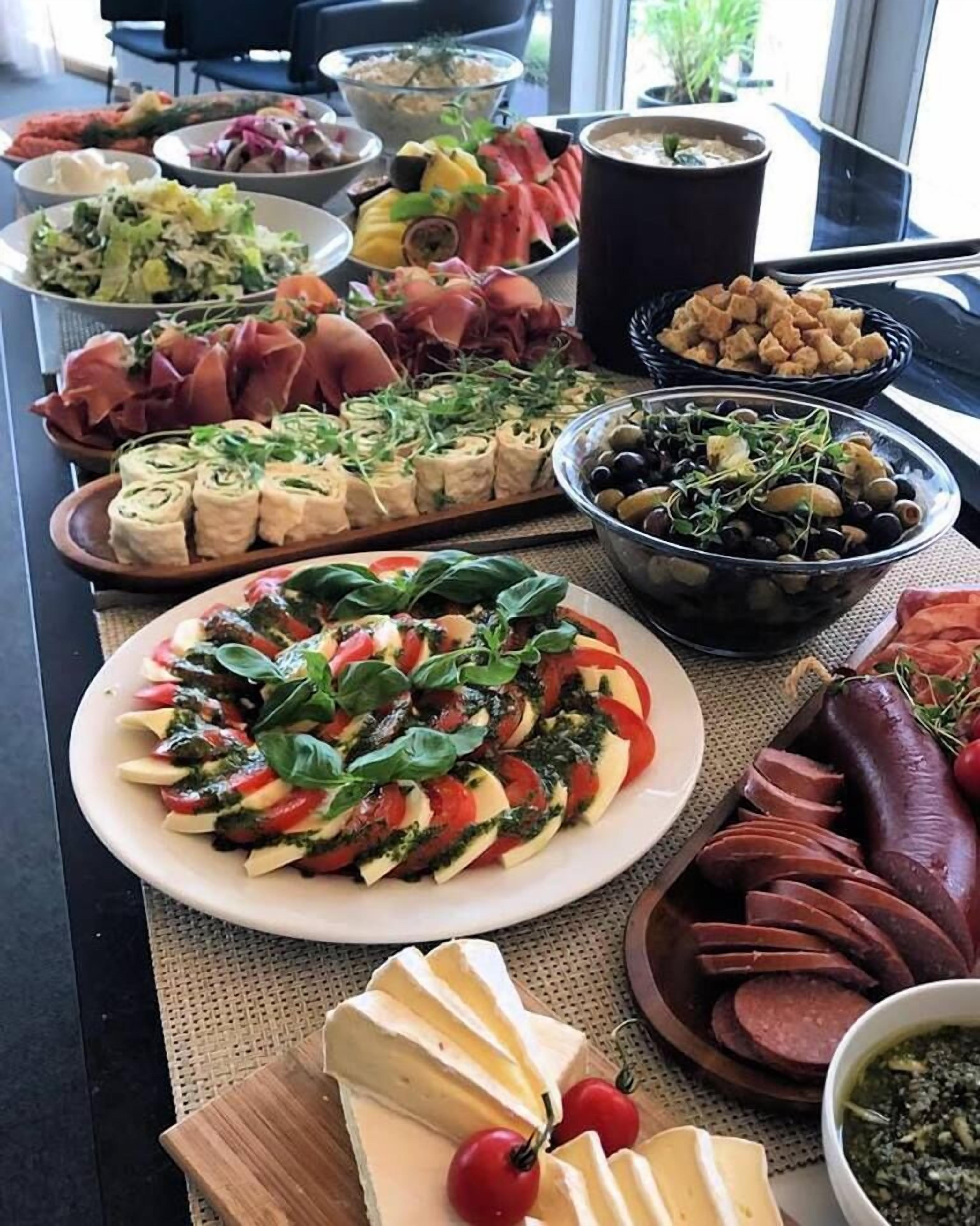Une table de buffet proposant divers plats, notamment des salades, des viandes et des fromages.