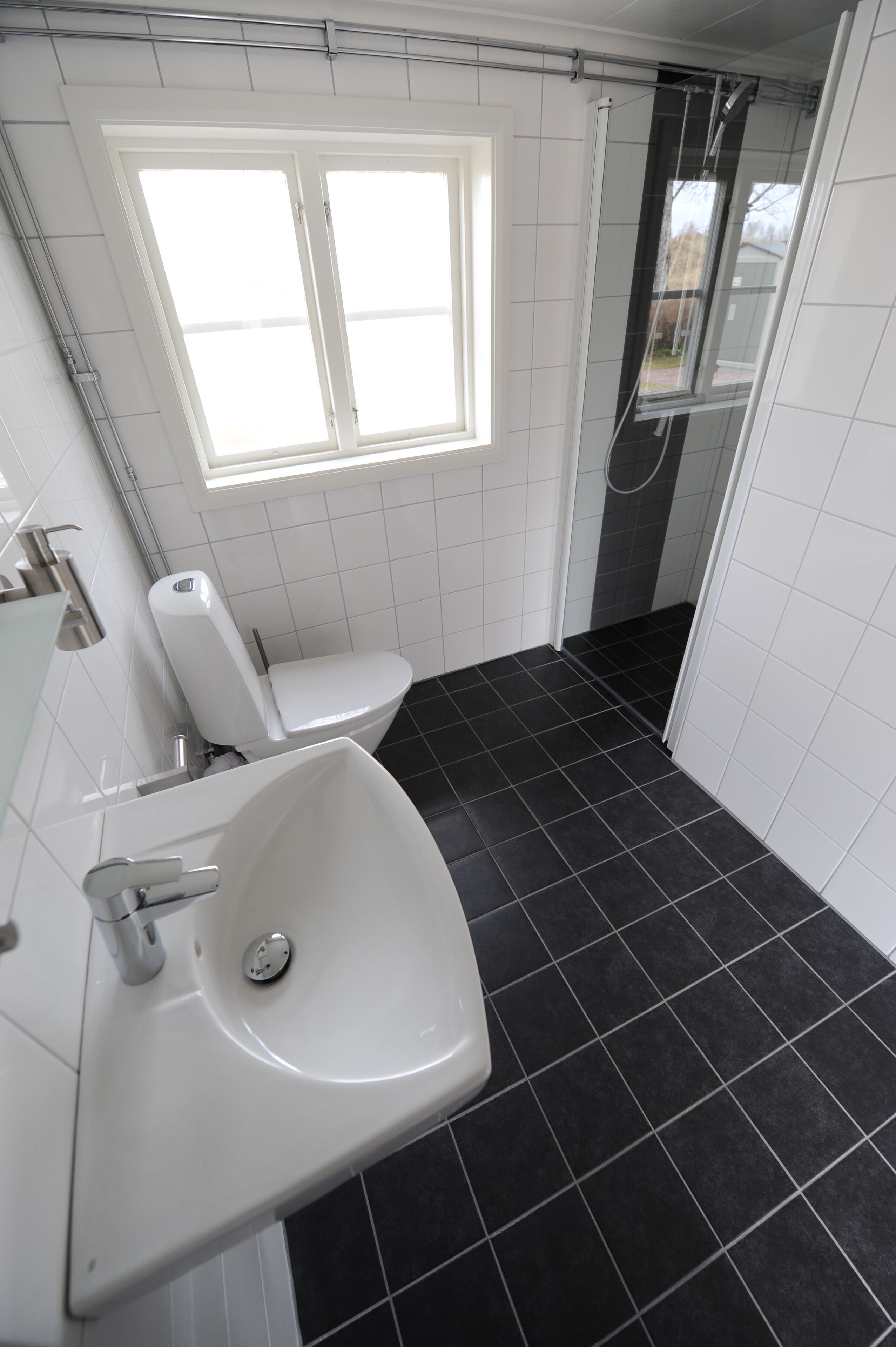 Ein Badezimmer mit weißem Waschbecken, Toilette und einem Fenster.